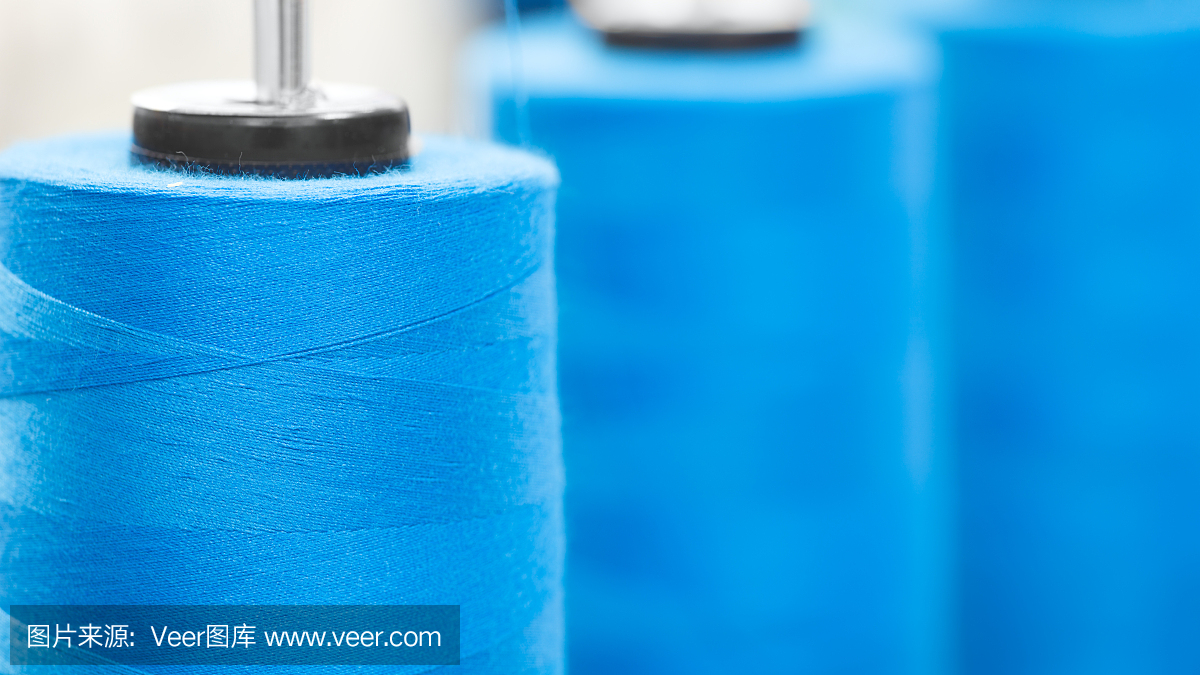 特写线轴与蓝色线工业纺织机器,蓝色纹理的网横幅背景
